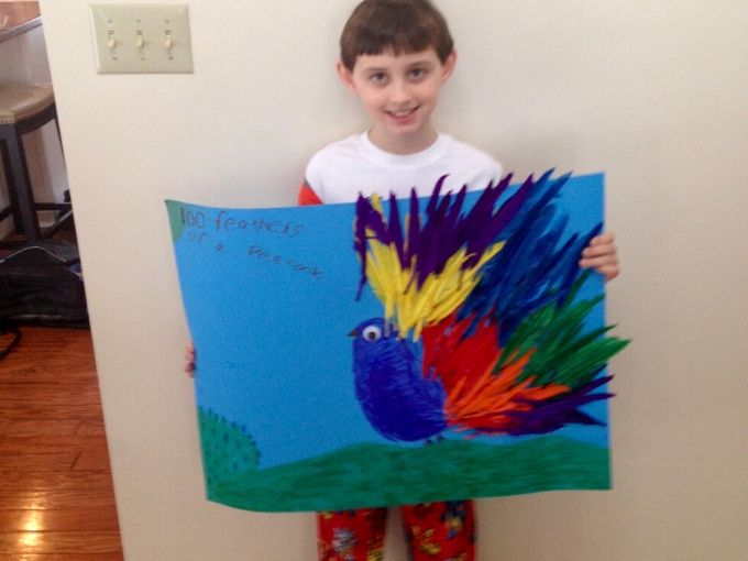 little boy holding a poster of a bird with colorful feathers