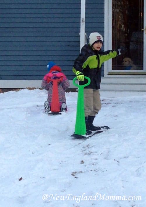 Kids outside in the snow on snow scooters