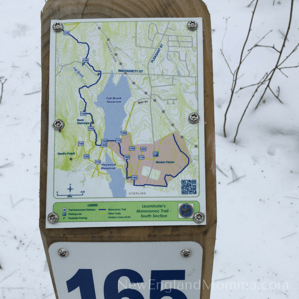 A trail map post in the snow.