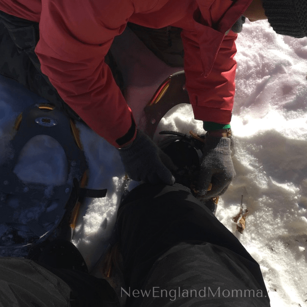 A mom friend helping a beginner with her snowshoes 