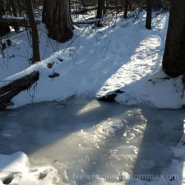 a frozen river next to a snow bank packed down with footprint trail