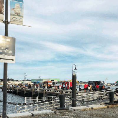a pier with food trucks on it next to the waterfront and people walking around
