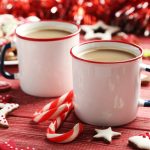 two mugs of hot cocoa in a festive red setting