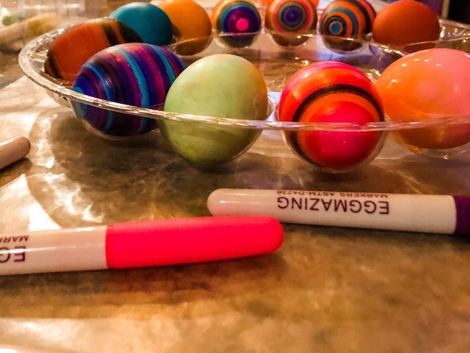 decorating eggs on the table with markers next to them 