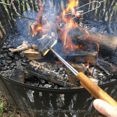 cooking 3 items over a campfire, pie iron, a hot dog and a marshmallow