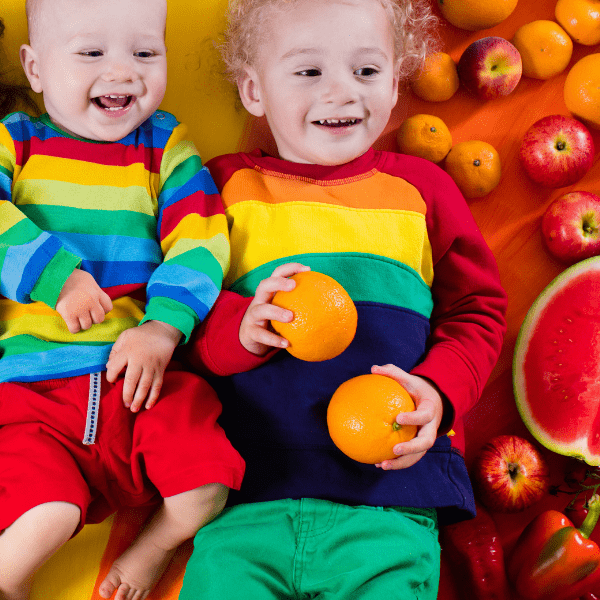 2 happy kids going on a car ride with a rainbow of fruits for car snacks