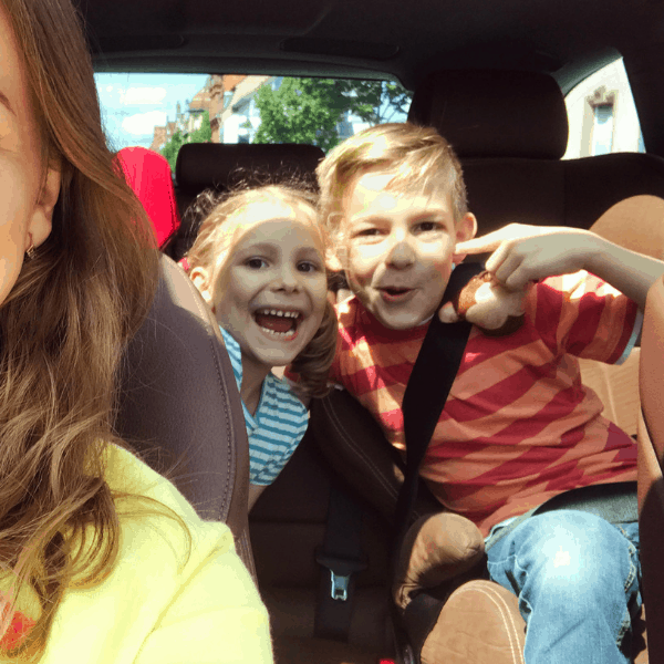 kids and mom in a car for a road trip with an apple snack