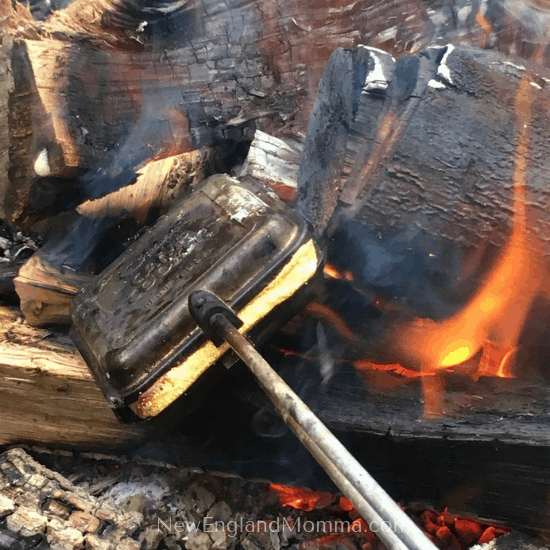 Pie iron in fire pit, cooking grilled cheese sandwich