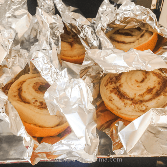 4 cinnamon rolls cooking up in oranges on the grill.