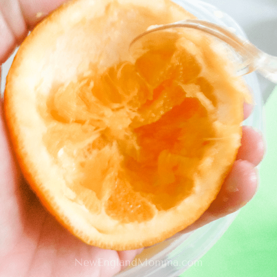 cleaning out the inside of an orange with a plastic fork
