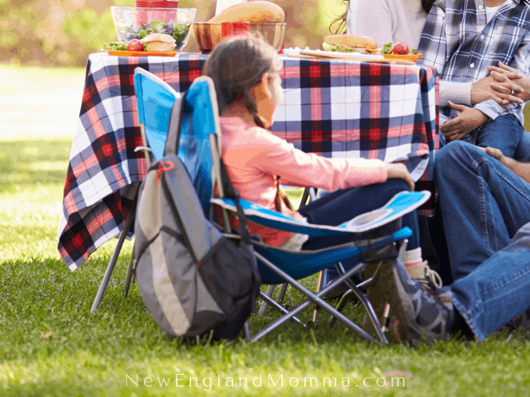 A family sitting around a picnic table playing a game while camping.