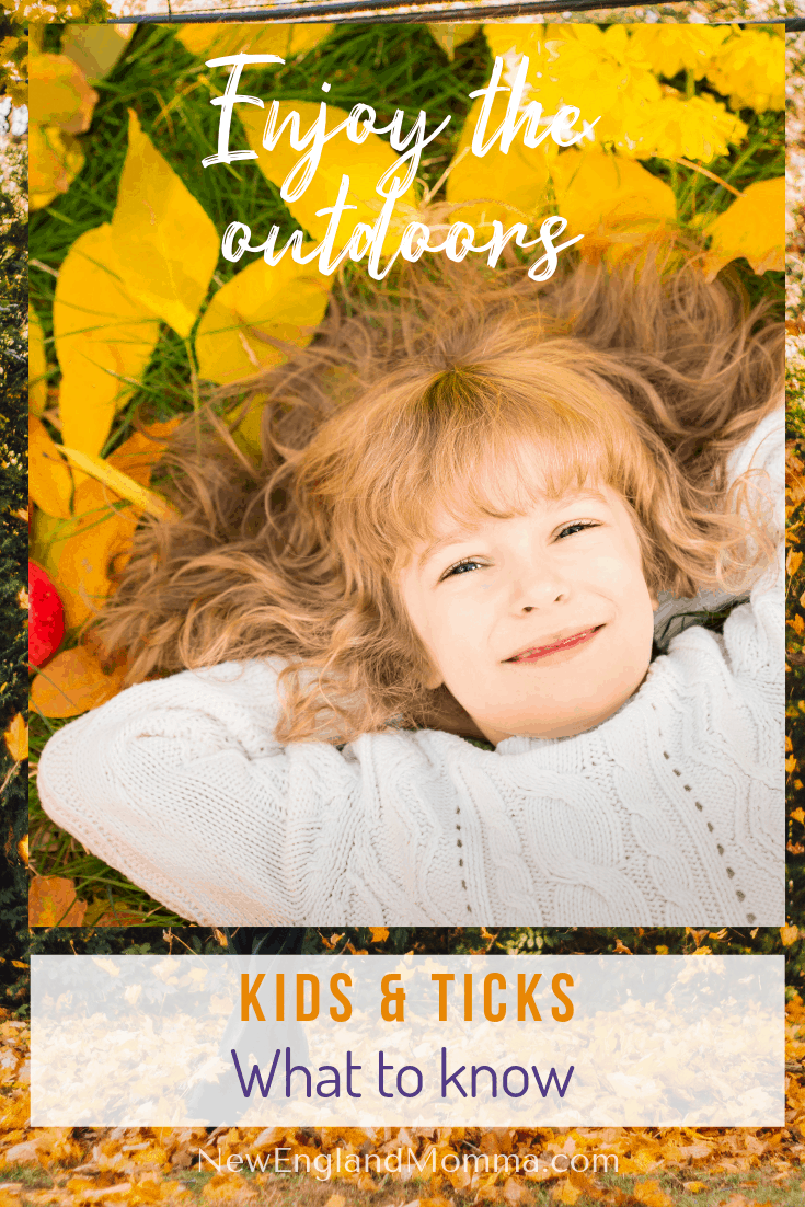 Child laying down on their back in fall leaves with no worries about ticks