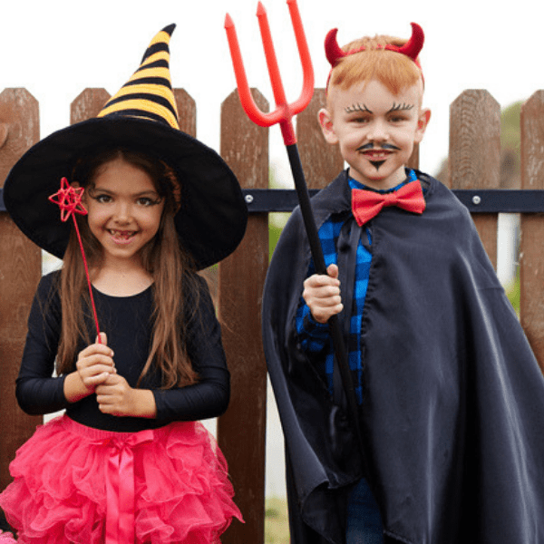 Kids dressed up in their Halloween costumes with big accessories like a witch hat or devil's pitch fork.