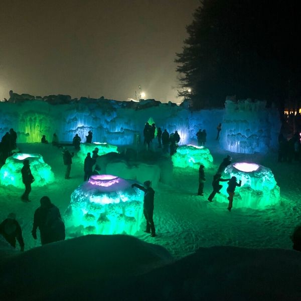 Looking down at the Ice Castles in Lincoln, NH while it is all lit up in fluorescent green and blue colors.  
