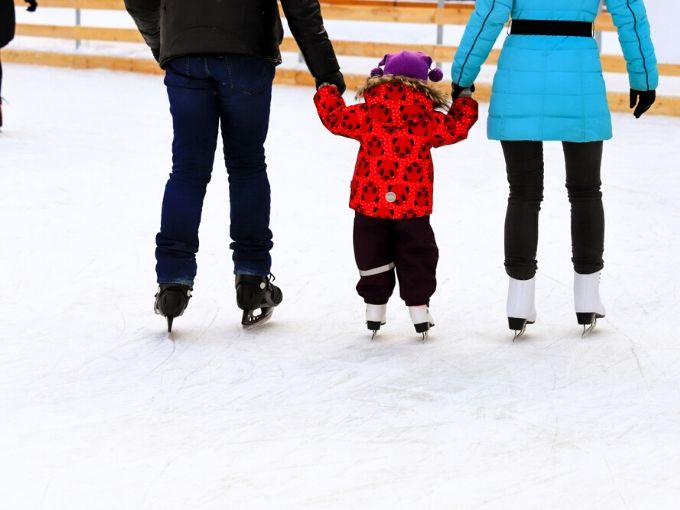Mom, dad and child holding hands skating away from us