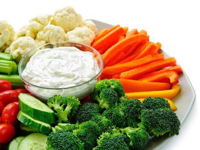 raw vegetables on a round tray with a white ranch dip in the center 