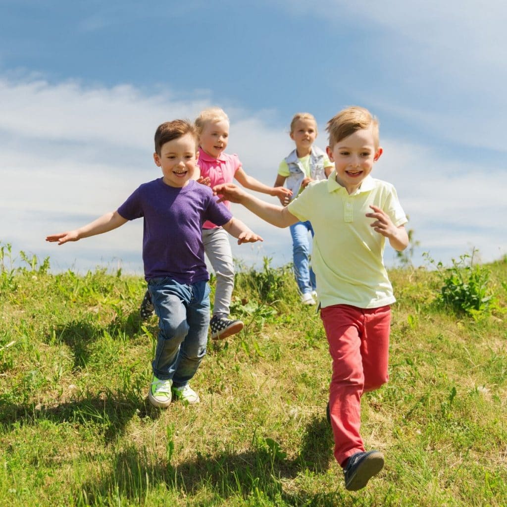 young kids running a field with smiles 