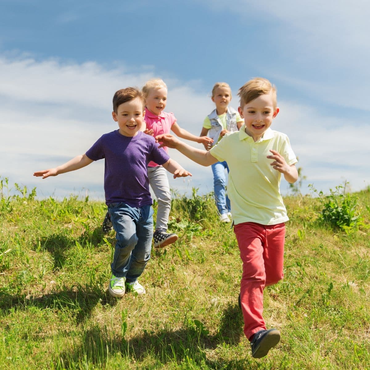 4 kids running in a field with big smiles