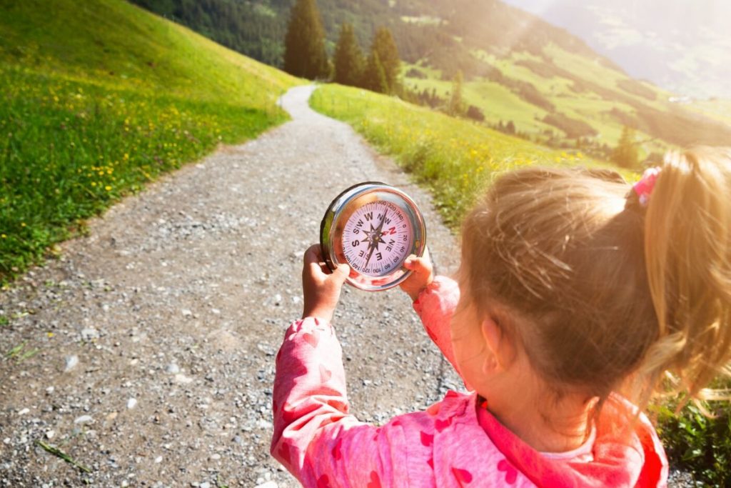 a little girl holding a compass while looking for letterboxes
