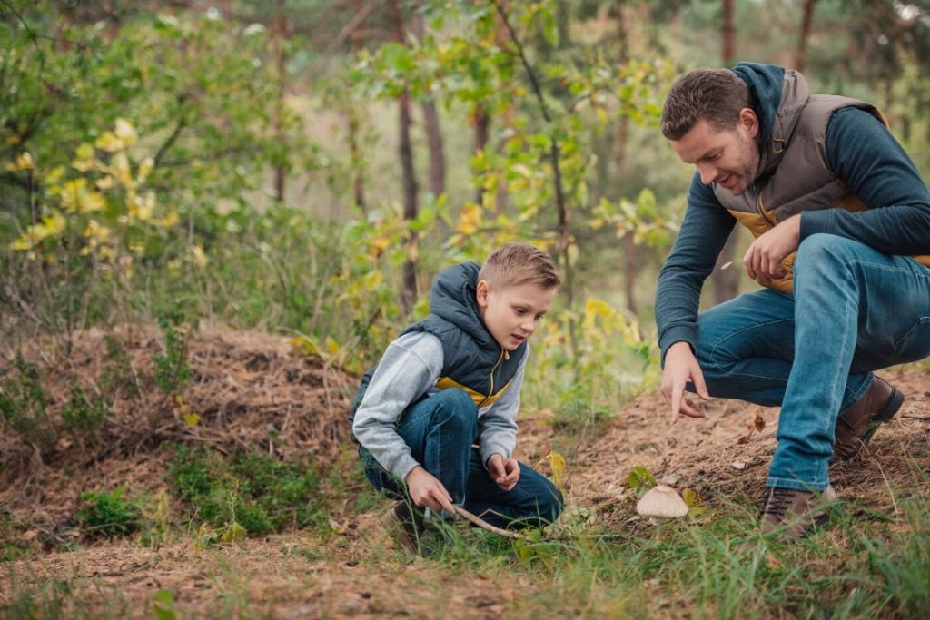 a dad and a boy in the woods looking for letterboxing treasure 