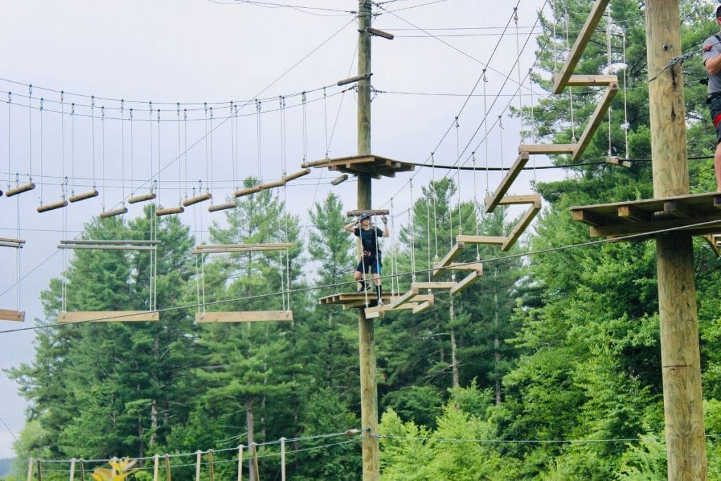 Teen boy on a wooden aerial ropes course at Boundless Adventures in Berlin, MA