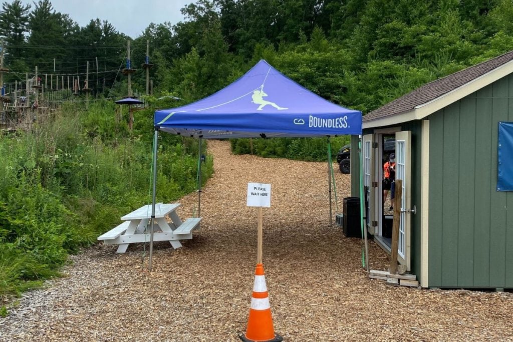 A path blocked by a safety cone and a blue canopy waiting for guests 