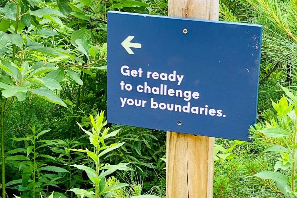 A sign that reads 'Get ready to challenge your boundaries' and an arrow pointing to the left 