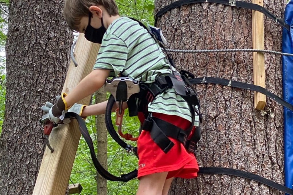 A tween aged boy releasing his clip at the end of the rope course upon completion at Boundless Adventures in Berlin, MA