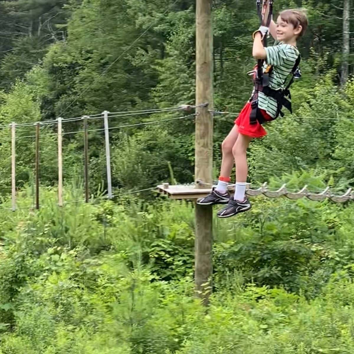 A child zip lining on a rope course