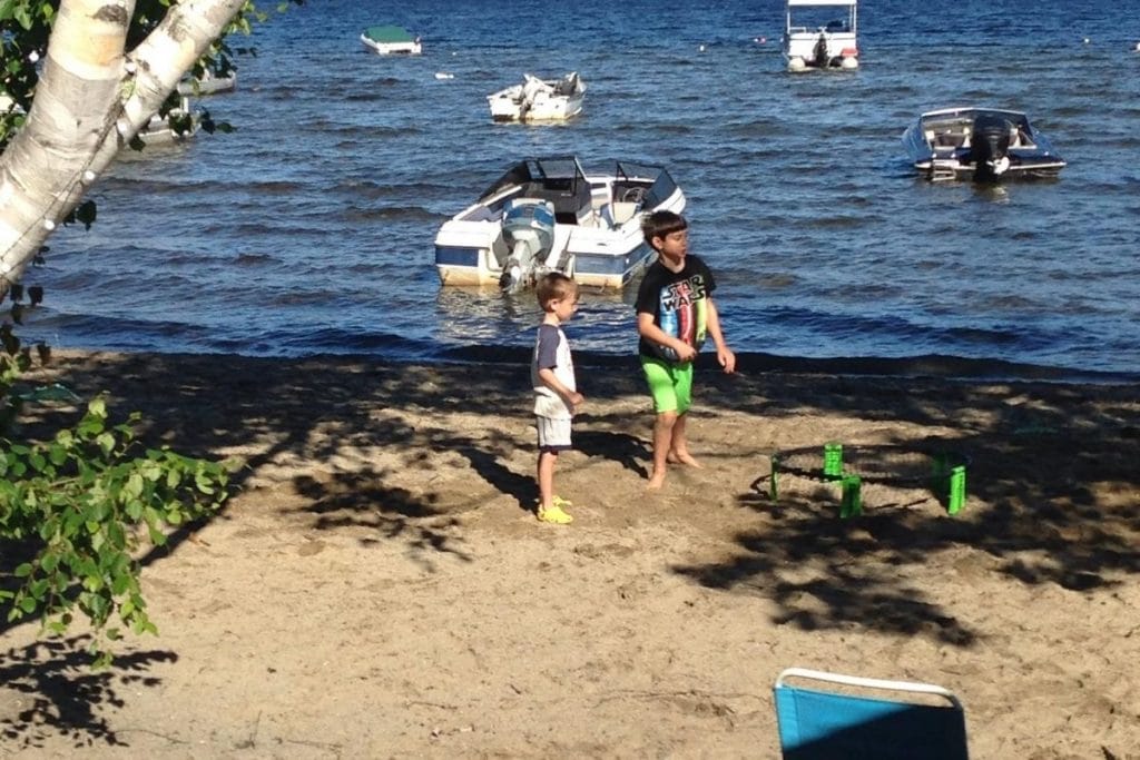 Two boys at a beach front campsite playing an outdoor ball game on the sand