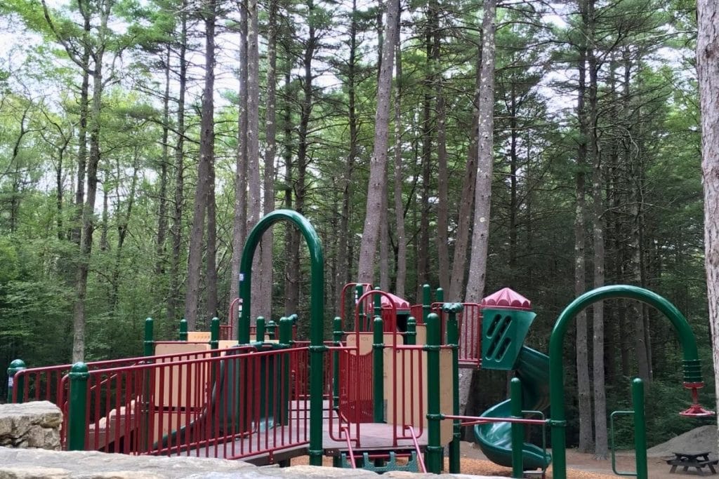 A green and red playground with climbing structures 