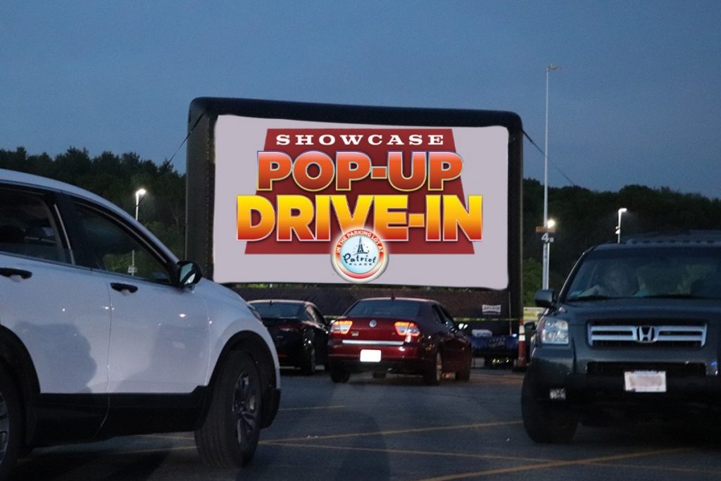 Cars at night parked in front of a drive in movie theatre 