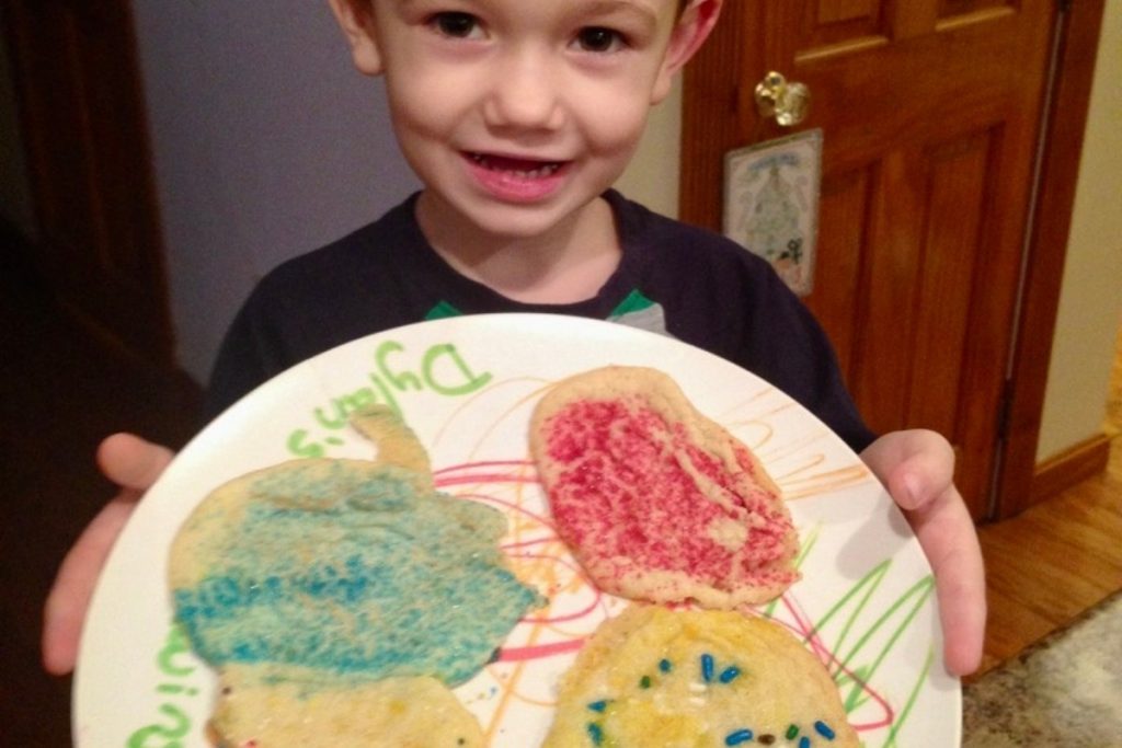 little boy holding a plate of hand decorated sugar cookies