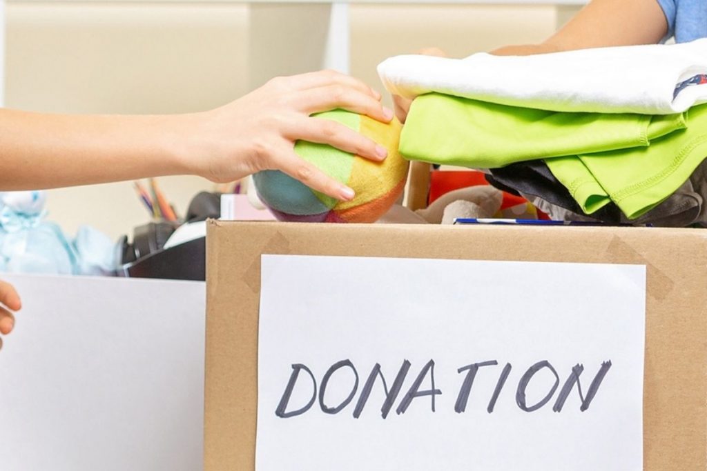 A hand donating a ball to a donation box