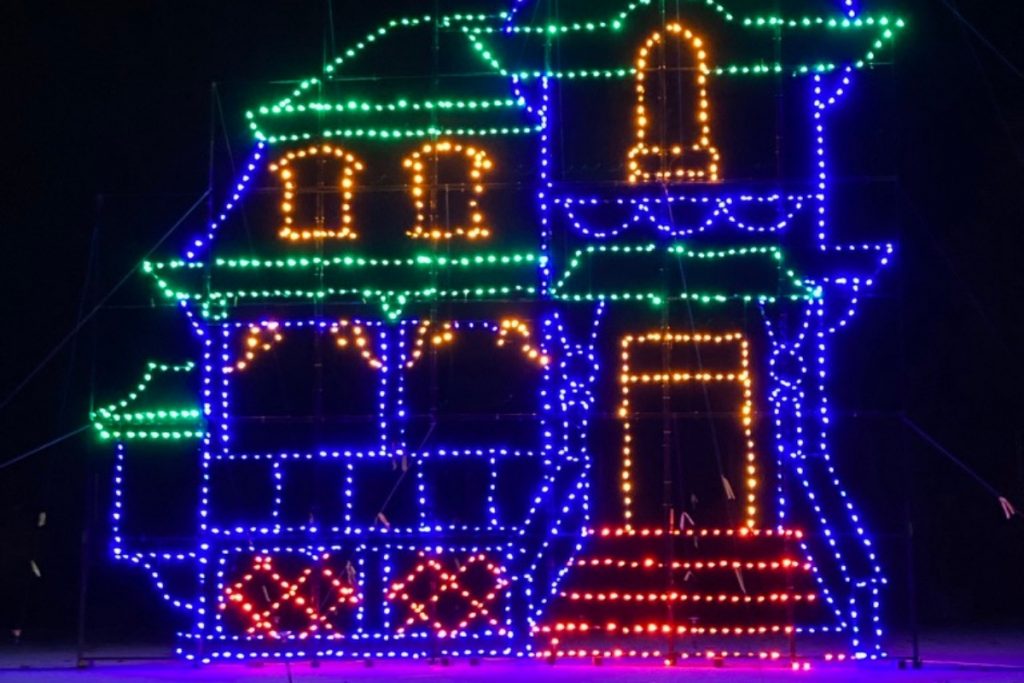 At night, the outline of a home in blue and green and red Christmas lights.