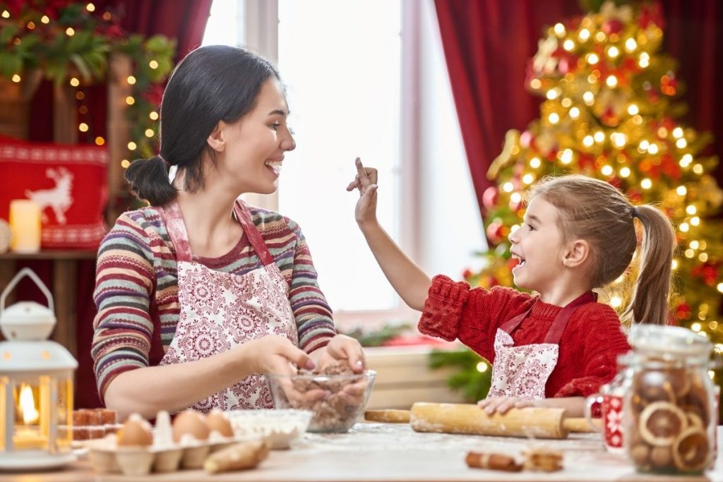 Mom and daughter laughing as they decorate cookies at Christmas time