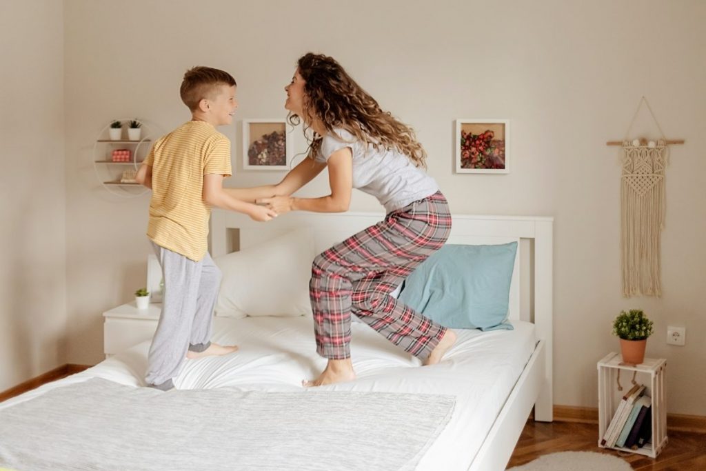 Mom and son happy dance on a bed 