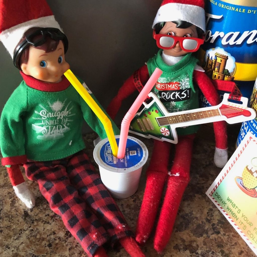 Two Christmas elves drinking hot cocoa from a straw