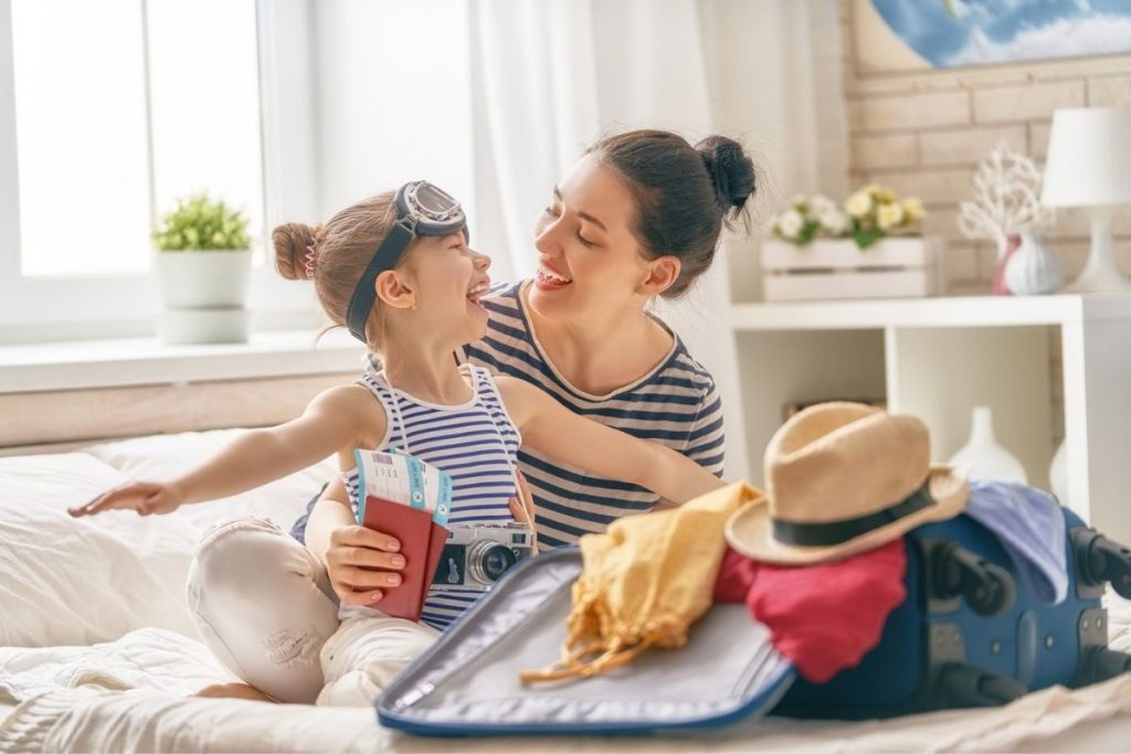 mom and daughter happy as they pack a suitcase for a trip