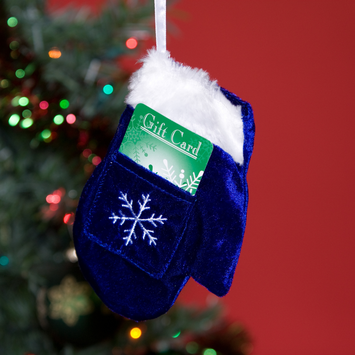 A stocking on a Christmas tree with a gift card sticking out of it
