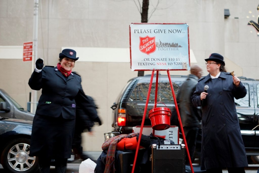 Two women being Salvation Army bell ringers outdoors