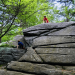 Kids climbing up a large boulder while hiking